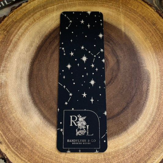 backside of bookmark displays a constellation pattern in silver foil. randylynnco logo is at the bottom of the bookmark. displayed on wooden block