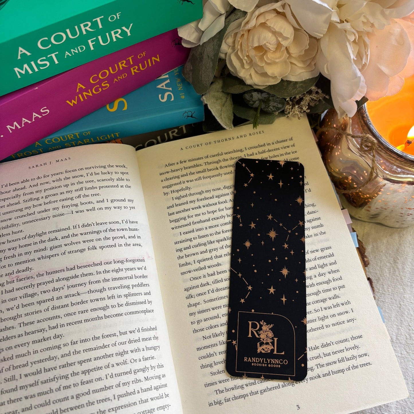 backside of rose gold bookmark displayed in open book. shows a constellation pattern and a randylynnco logo