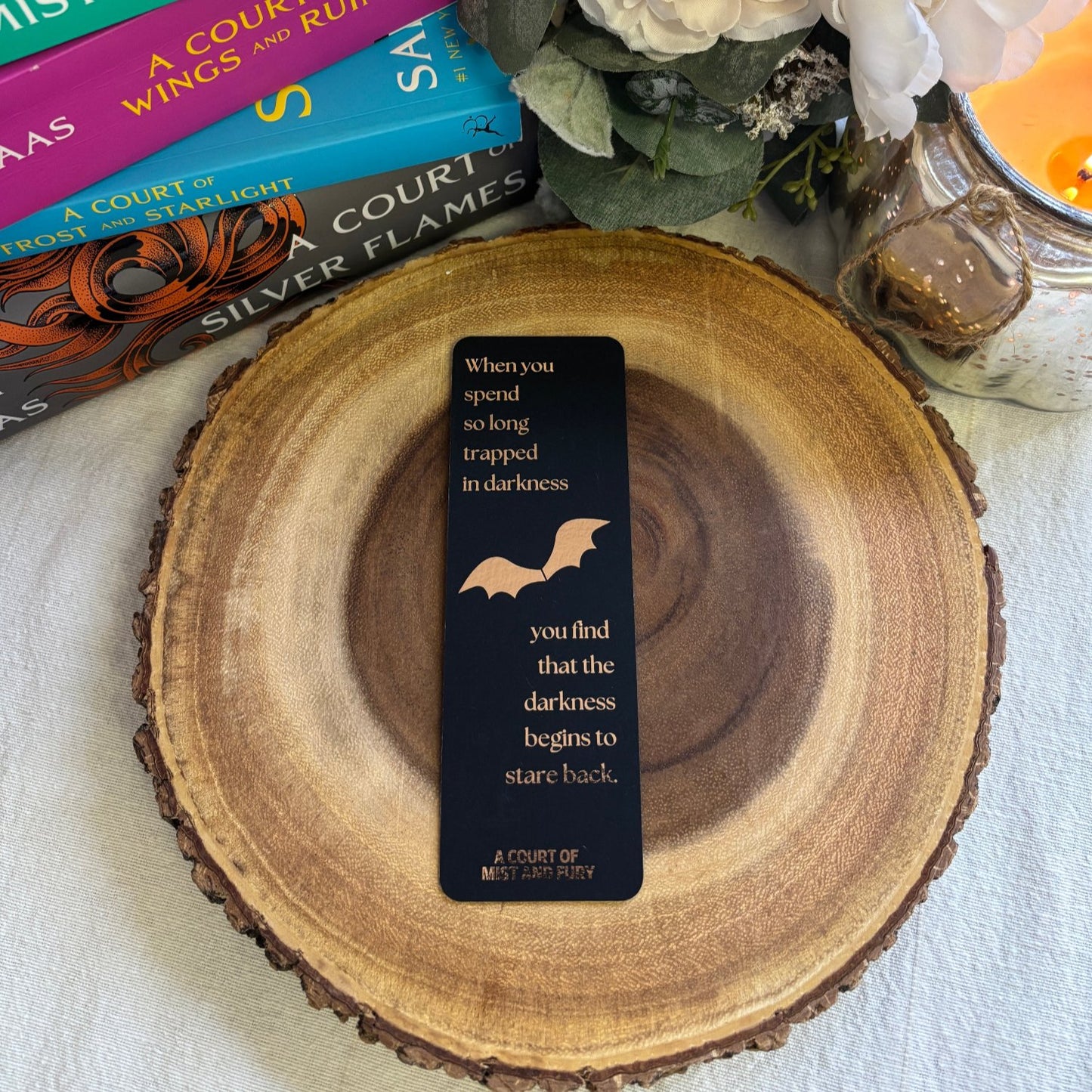 black bookmark with rose gold foil. quote reads, &quot;when you spend so long trapped in darkness, you find that the darkness begins to stare back&quot;. graphic of bat wings sits in between the quote